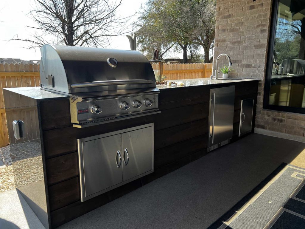 Outdoor kitchen with built-in grill under a covered patio addition, Austin TX