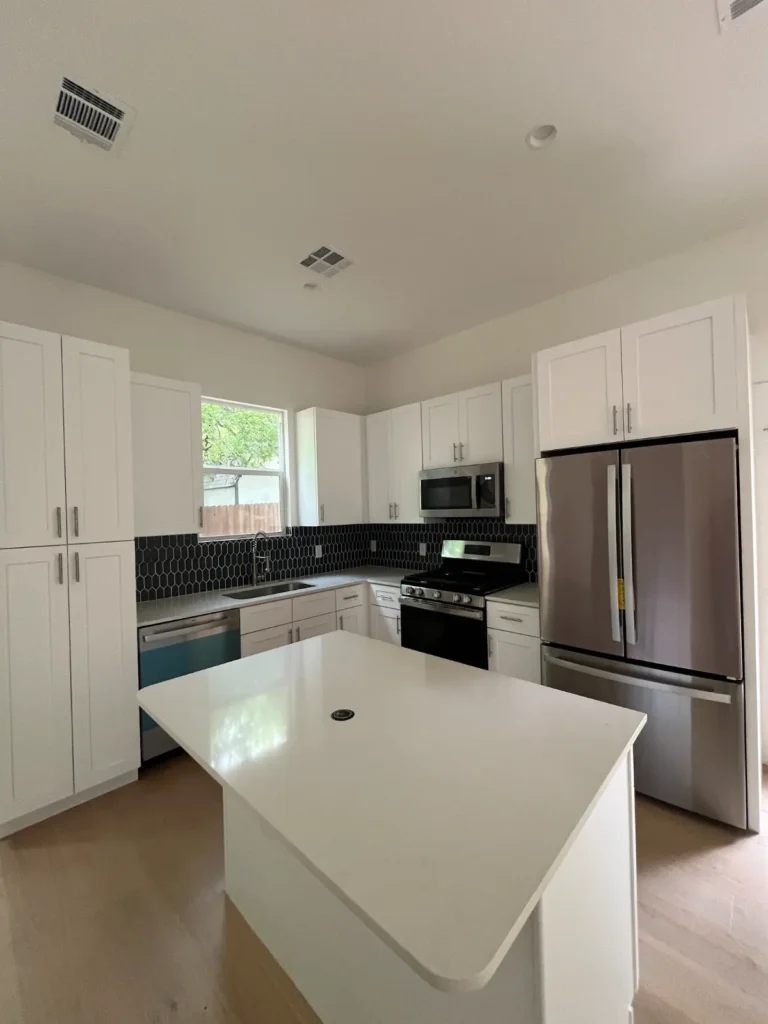 Kitchen with white cabinets and black tile backsplash in a new ADU at 500 Capitol Drive, Austin TX